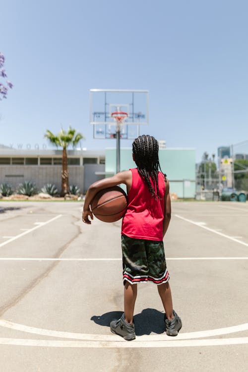Free Boy in Red Jersey Standing on a Basketball Court Stock Photo