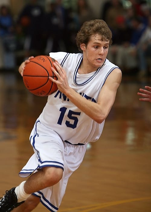 Free Boy in Basketball Jersey Carrying Basketball at Basketball Court Stock Photo