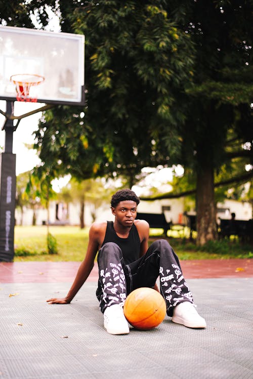 Free Young Man Sitting on the Ground at a Basketball Court Stock Photo